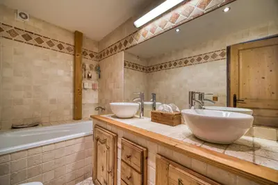a bathroom with two sinks and a bath tub and a tubermott at Chalet Nessa in Combloux