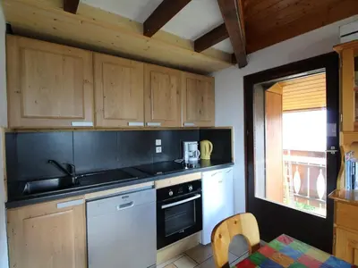 a kitchen with wooden cabinets and a white dishwasher at Appartement cosy 6 pers. au pied des pistes, balcon sud-ouest, proche centre, ski-in/ski-out - FR-1-572-155 in Arâches-la-Frasse