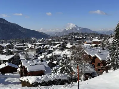 a town covered in snow with mountains in the background at Studio 4 pers, centre village, 450m télécabine, balcon, casier à skis, animaux acceptés - FR-1-572-211 in Arâches-la-Frasse