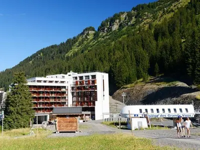 a large building with people standing in front of a mountain at Flaine: 4P au pied des pistes, piscine, parking, 8 pers - FR-1-687-15 in Arâches-la-Frasse