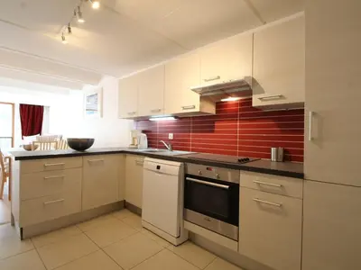 a kitchen with white cabinets and a red wall at Appartement rénové 3 pièces, 8 pers, proche pistes et commerces - Flaine Forum - FR-1-687-39 in Arâches-la-Frasse