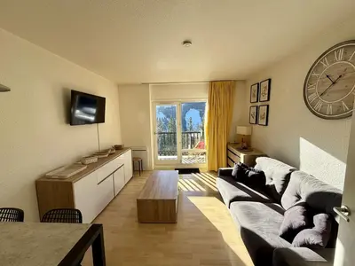 a living room with a couch and a clock on the wall at Studio 4 pers, proche pistes, animaux bienvenus - FR-1-687-37 in Arâches-la-Frasse