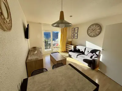 a living room with a couch and a clock on the wall at Studio 4 pers, proche pistes, animaux bienvenus - FR-1-687-37 in Arâches-la-Frasse