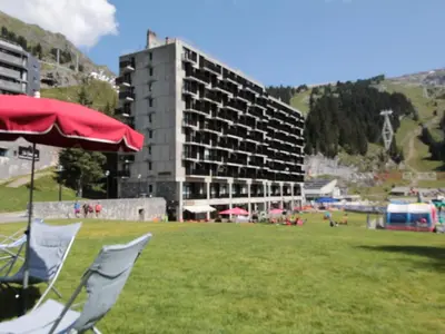 a red umbrella and a chair in a field with a building at Appartement 3 pièces pour 8 pers, au pied des pistes – Résidence Aldebaran, Flaine Forum - FR-1-687-57 in Arâches-la-Frasse