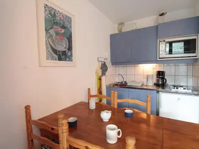 a kitchen with a wooden table and blue cabinets at Studio lumineux avec balcon et vue sur pistes, animaux admis - FR-1-687-61 in Arâches-la-Frasse