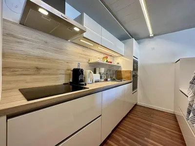 a kitchen with white cabinets and a wooden wall at 3 Pièces Rénové pour 6 Pers. à Flaine Forum - 50m², Proche Pistes et Commerces - FR-1-687-35 in Arâches-la-Frasse