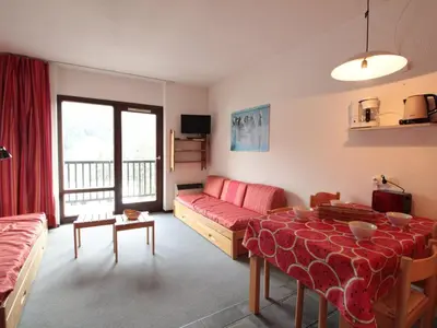 a living room with a red couch and a table at Studio Coin Montagne 25m² à Flaine, balcon et proximité pistes - FR-1-687-42 in Arâches-la-Frasse