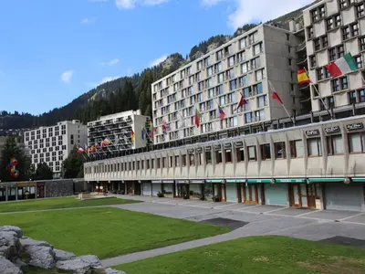 a large building with a grass field in front of it at 2 pièces à Flaine, 6 couchages, à 50m des pistes - FR-1-687-89 in Arâches-la-Frasse