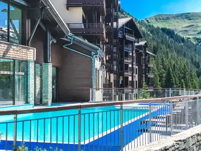 a swimming pool in front of a building with a mountain at South facing 2-bed apartment with fireplace, Terrasses dEos in Flaine