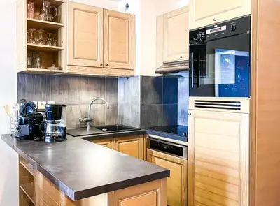 a kitchen with wooden cabinets and a black appliance at South facing 2-bed apartment with fireplace, Terrasses dEos in Flaine