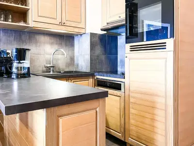 a kitchen with wooden cabinets and a black counter top at South facing 2-bed apartment with fireplace, Terrasses dEos in Flaine