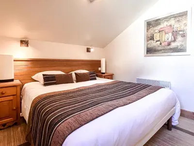 a bedroom with a large bed with a wooden headboard at South facing 2-bed apartment with fireplace, Terrasses dEos in Flaine