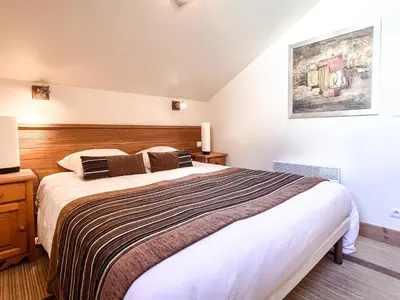 a bedroom with a large bed with a wooden headboard at South facing 2-bed apartment with fireplace, Terrasses dEos in Flaine