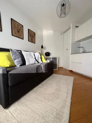 a living room with a black couch and a kitchen at Green Apple Chamonix, centre, parking, ski-in/out in Chamonix-Mont-Blanc