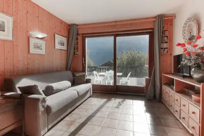 a living room with a couch and a large window at Les Terrasses de Planpraz - 8min Walk to Center - Quiet - Perfect for Hiking in Chamonix-Mont-Blanc