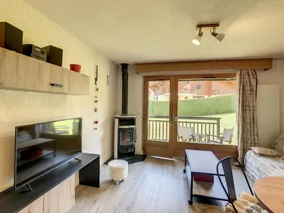 a living room with a television and a living room with a table at Charmant 2P à Combloux avec terrasse, parking et casier à ski - FR-1-560-101 in Combloux