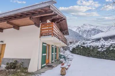 a building with benches in the snow with mountains at Chalet Bossons - Welkeys in Chamonix-Mont-Blanc
