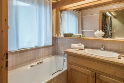a bathroom with a tub and a sink and a mirror at Appartement Lanura - Welkeys in Megève