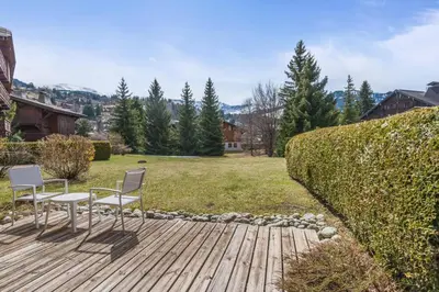 two chairs and a table on a wooden deck at Appartement Lanura - Welkeys in Megève