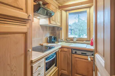 a kitchen with wooden cabinets and a sink and a window at Appartement Lanura - Welkeys in Megève