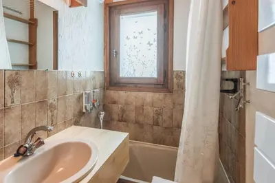 a bathroom with a sink and a tub and a window at Appartement Warens - Welkeys in Megève