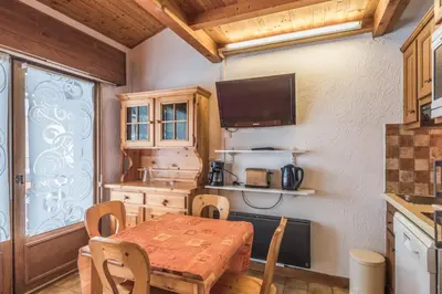 a dining room with a table and a kitchen at Appartement Warens - Welkeys in Megève