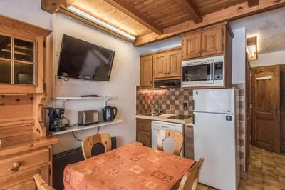 a kitchen with a table and a white refrigerator at Appartement Warens - Welkeys in Megève