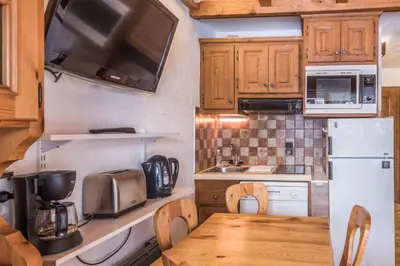 a kitchen with a wooden table and a refrigerator at Appartement Warens - Welkeys in Megève