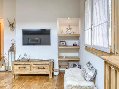 a living room with a couch and a tv on a wall at Appartement lumineux 2 chambres proche centre, animaux admis, parking, WiFi - FR-1-453-296 in Megève