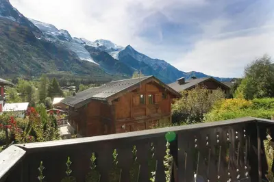a wooden house on a balcony with mountains in the background at Le Chamouny- Family Apt - Central - Quiet - Hikeing & Rock Climbing Close by in Chamonix-Mont-Blanc