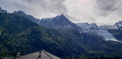 a view of a mountain with trees and a building at Le Chamouny- Family Apt - Central - Quiet - Hikeing & Rock Climbing Close by in Chamonix-Mont-Blanc