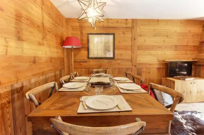 a dining room with a wooden table and chairs at Clos des Vorgeats - Duplex Beside Golf Course - Patio - UTMB in Chamonix-Mont-Blanc