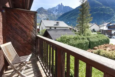 a wooden balcony with a chair and mountains at Clos des Vorgeats - Duplex Beside Golf Course - Patio - UTMB in Chamonix-Mont-Blanc