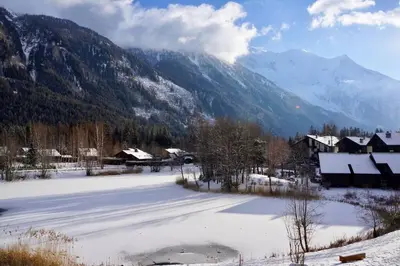 a snow covered village with mountains in the background at Modern 2BR 5* pool gym spa garage Mont-Blanc view in Chamonix-Mont-Blanc