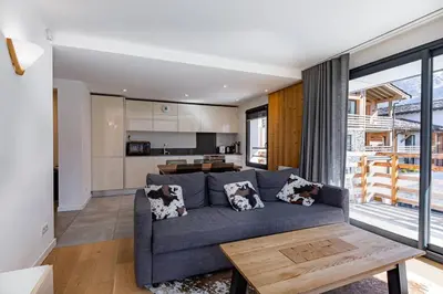 a living room with a blue couch and a kitchen at Modern 2BR 5* pool gym spa garage Mont-Blanc view in Chamonix-Mont-Blanc
