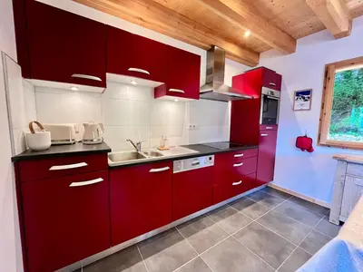 a kitchen with red cabinets and a sink at Chalet tradition 6 pers avec cheminée, balcon et parking à Samoëns - FR-1-624-124 in Samoëns