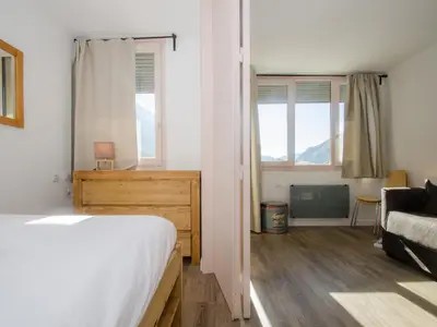 a bedroom with a bed and a couch and windows at Appartement cosy à Chamonix Sud pour 4 pers, animaux acceptés - FR-1-343-157 in Chamonix-Mont-Blanc