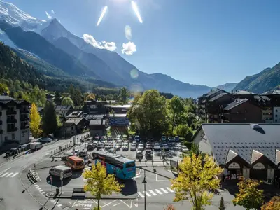 a town with a parking lot with mountains in the background at Appartement cosy à Chamonix Sud pour 4 pers, animaux acceptés - FR-1-343-157 in Chamonix-Mont-Blanc