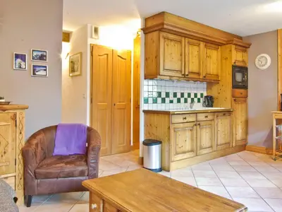 a kitchen with wooden cabinets and a chair and a table at Appartement 6 pers, Chamonix, Parking - FR-1-343-169 in Chamonix-Mont-Blanc