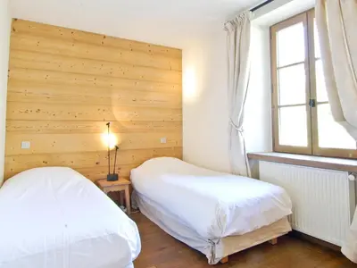two beds in a bedroom with a wooden wall at Appartement spacieux à Chamonix, 3 chambres, WiFi - FR-1-343-176 in Chamonix-Mont-Blanc