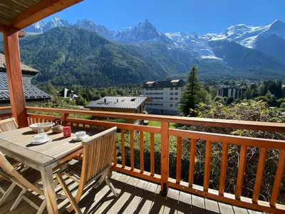 a wooden deck with a table and chairs on a balcony with mountains at Appartement spacieux à Chamonix, 3 chambres, WiFi - FR-1-343-176 in Chamonix-Mont-Blanc