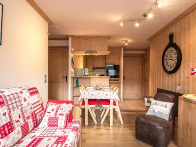 a living room with a table and chairs and a clock at Bel appartement au cœur de Chamonix, près des pistes, avec parking - FR-1-343-163 in Chamonix-Mont-Blanc