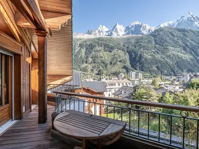 a porch with a bench on a balcony with mountains at Bel appartement duplex pour 8, proche pistes à Chamonix avec wifi et parking - FR-1-343-188 in Chamonix-Mont-Blanc