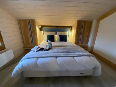 a bedroom with a large bed with a teddy bear sitting on it at Bel duplex à Chamonix avec poêle à bois, WiFi, parking - FR-1-343-166 in Chamonix-Mont-Blanc
