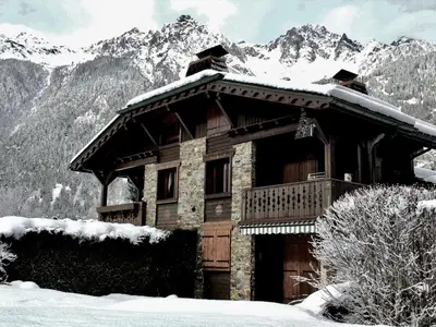 a log cabin in the snow with mountains in the background at Bel duplex à Chamonix avec poêle à bois, WiFi, parking - FR-1-343-166 in Chamonix-Mont-Blanc
