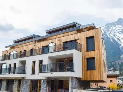 a building with a mountain in the background at Duplex 3 étoiles pour 6 pers, Chamonix, parking privé - FR-1-343-189 in Chamonix-Mont-Blanc