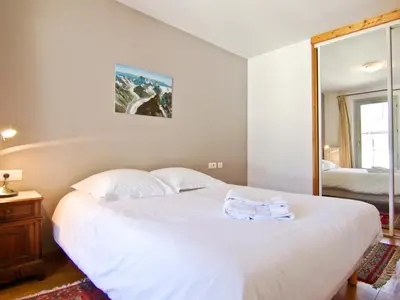 a bedroom with a large white bed and a mirror at Charmant duplex au cœur de Chamonix avec wifi et animaux admis - FR-1-343-183 in Chamonix-Mont-Blanc
