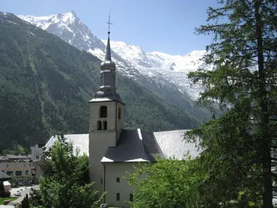 a church with a steeple in front of a mountain at Charmant duplex au cœur de Chamonix avec wifi et animaux admis - FR-1-343-183 in Chamonix-Mont-Blanc