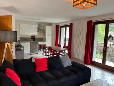 a living room with a black couch and a kitchen at Charmant appartement au cœur de Chamonix avec parking et animaux acceptés - FR-1-343-187 in Chamonix-Mont-Blanc