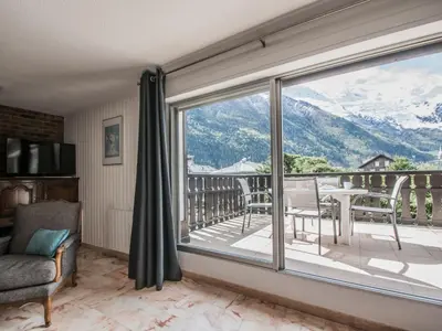 a living room with a balcony with a table and chairs at Appartement spacieux à Chamonix avec terrasse et parking privé - FR-1-343-173 in Chamonix-Mont-Blanc